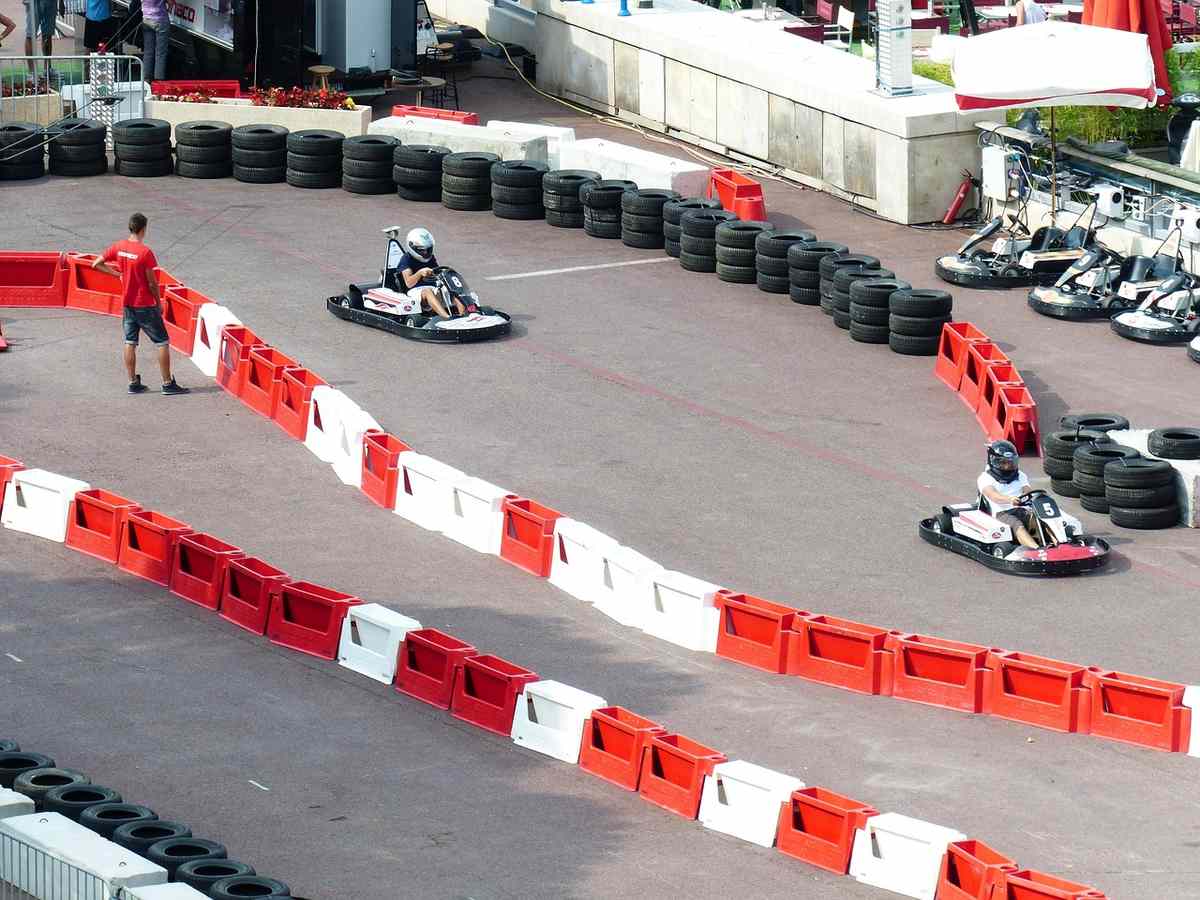 Deux personnes conduisent des karting sur un circuit avec barrières rouges Deux personnes conduisent des karting sur un circuit avec barrières rouges