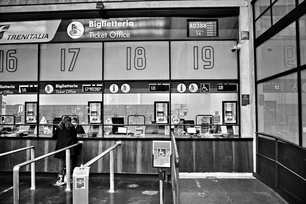 Guichets de Trenitalia avec des numéros, personnes en file d'attente pour acheter des billets Guichets de Trenitalia avec des numéros, personnes en file d'attente pour acheter des billets