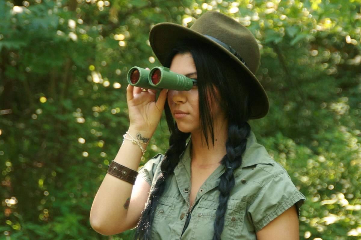 Femme avec jumelles dans la forêt