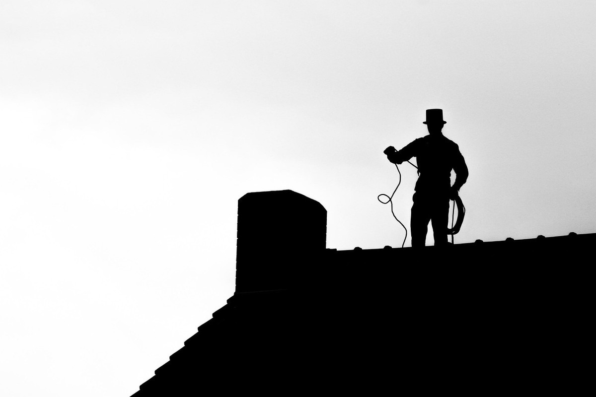 Silhouette d'un ramoneur sur toit, chapeau haut, corde à la main Silhouette d'un ramoneur sur toit, chapeau haut, corde à la main