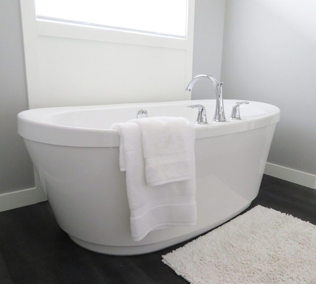Une baignoire blanche avec robinet, serviettes et tapis dans une salle de bain