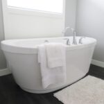Une baignoire blanche avec robinet, serviettes et tapis dans une salle de bain