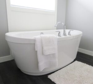 Une baignoire blanche avec robinet, serviettes et tapis dans une salle de bain