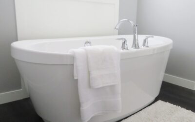 Une baignoire blanche avec robinet, serviettes et tapis dans une salle de bain